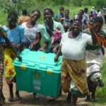 happy malawian group carrying shelterbox crate