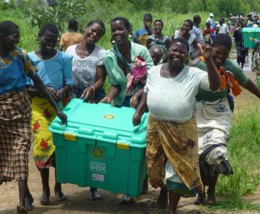 happy malawian group carrying shelterbox crate