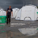shelterbox volunteers with tents on muddy ground
