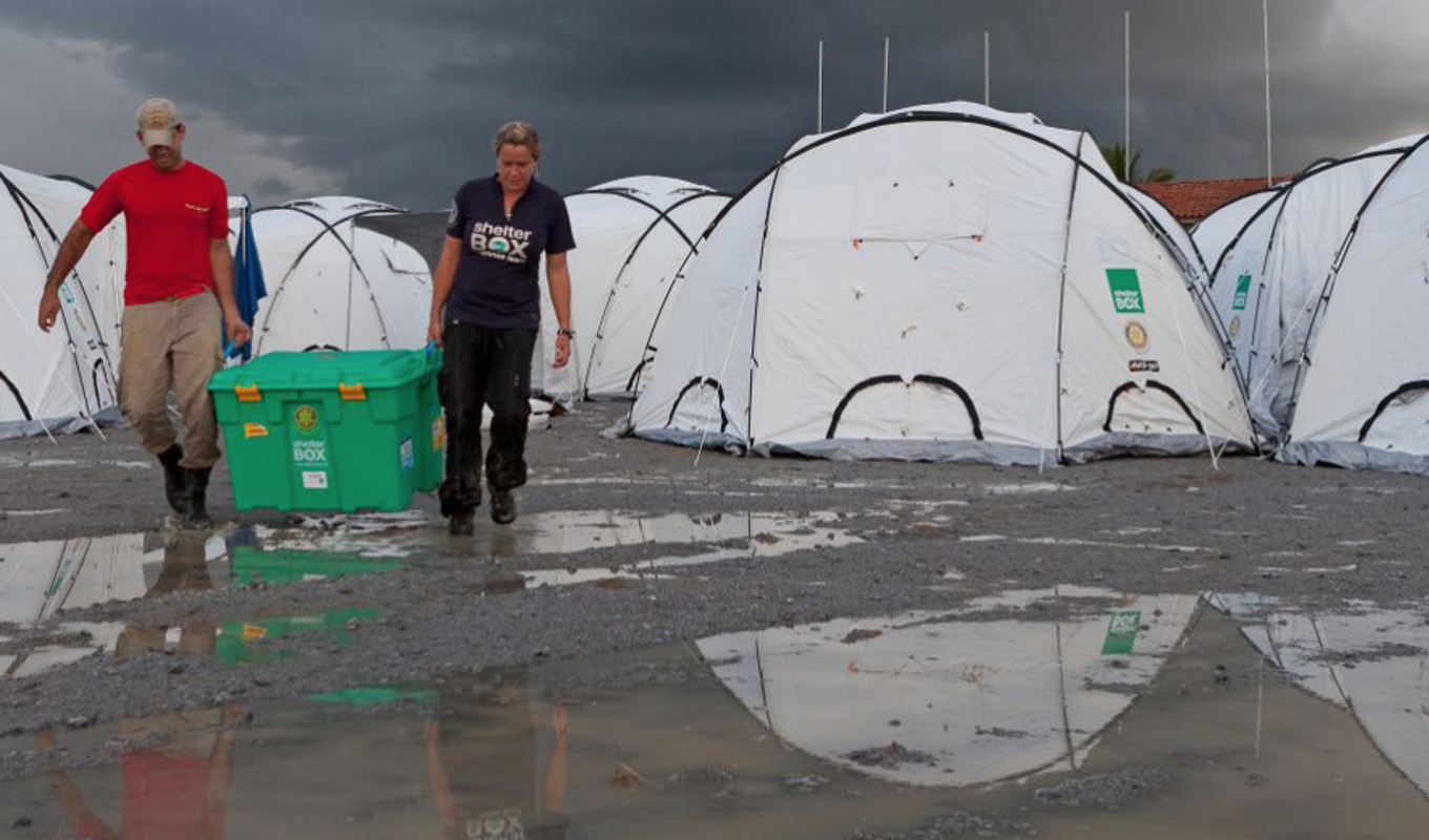 shelterbox volunteers with tents on muddy ground